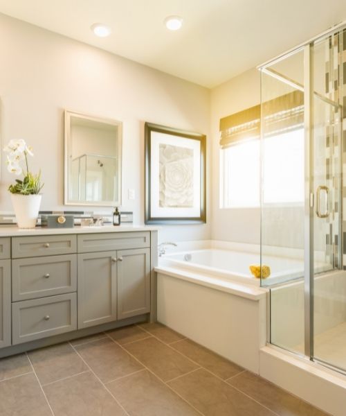 Clean bathroom with tile flooring, a deep bathtub, and a glass shower.