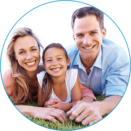 A happy father, mother, and young daughter laying in the grass together.