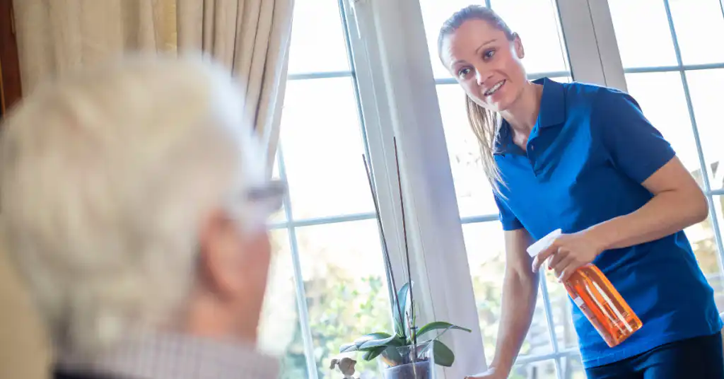 Professional house cleaner smiling and talking to an elderly client.